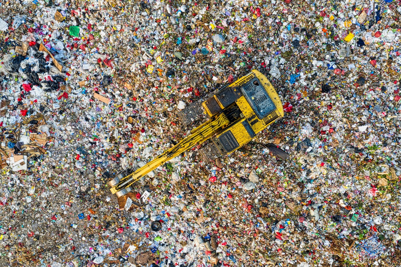 Aerial shot of a landfill with a yellow excavator in South Tangerang, Indonesia.